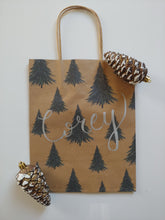 Load image into Gallery viewer, Would you like a personalized kraft bag for a holiday gift for a loved one? This tree gift bag is a classic one to give this holiday season. Each gift bag can be personalized with a name written in calligraphy with choice of font colour. Medium kraft bag dimensions 8 x 10 inches (20.3 cm x 25.4 cm)