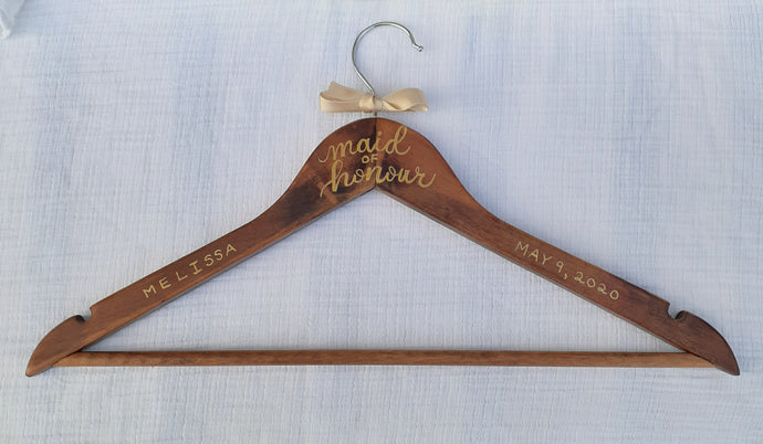 If you are looking for a perfect gift for your maid of honour here is a custom hanger to accent her beautiful dress.  Wood hangers are hand-lettered with the maid of honour’s name and the wedding date. 