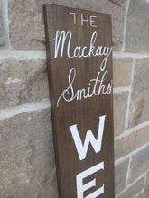 Load image into Gallery viewer, A personalized welcome sign can be a warm, welcoming piece at the entrance of your home with a family name that can be added to the top of the sign. Each sign is vertically hand lettered with “WELCOME” that is painted white down the center of the sign on a 48x7 inch solid wood sign. Each sign is stained in your choice of colour and sealed for weather resistance. Are you looking for custom font colour please let me know! Please allow me up to two weeks to produce your Welcome sign.