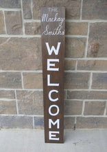 Load image into Gallery viewer, A personalized welcome sign can be a warm, welcoming piece at the entrance of your home with a family name that can be added to the top of the sign. Each sign is vertically hand lettered with “WELCOME” that is painted white down the center of the sign on a 48x7 inch solid wood sign. Each sign is stained in your choice of colour and sealed for weather resistance. Are you looking for custom font colour please let me know! Please allow me up to two weeks to produce your Welcome sign.