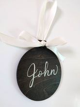 Load image into Gallery viewer, Wood ornaments are stained your choice of colour, and can be personalized in your choice of font colour.  Each ornament has a ribbon tied in a bow included.  Baltic Birch 4 inch round, 3mm thick.

